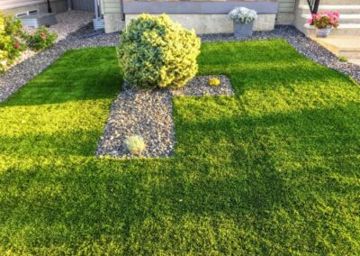 Artificial grass front yard with rock garden and potted flowers.