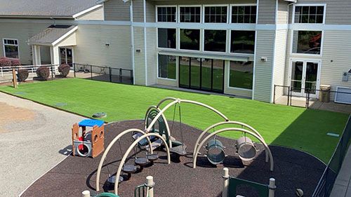 Children's playground with synthetic grass outside school.
